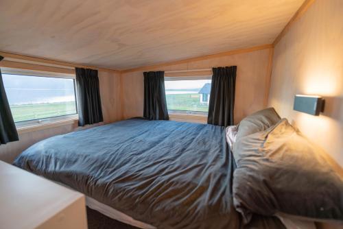 ein Schlafzimmer mit einem Bett und zwei Fenstern in der Unterkunft Tiny Piece of Paradise - Te Anau Tiny House in Te Anau