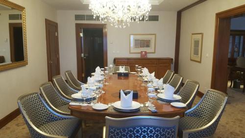 een lange houten tafel met stoelen en een kroonluchter bij Abha Palace Hotel in Abha