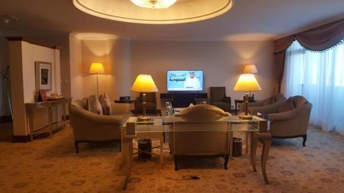 a living room with couches a table and a television at Abha Palace Hotel in Abha