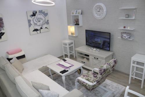 a living room with a white couch and a tv at Apartmani Porodica Karalić Vlašić in Vlasic