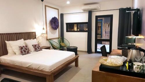 a bedroom with a bed in a room with a table at L'Hédone, hôtel de charme in Ouagadougou