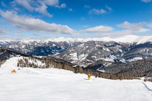 two people are skiing down a snow covered mountain at Hotel Guesthouse Dalnig in Bad Kleinkirchheim