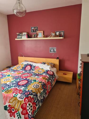 une chambre avec un lit et un mur rouge dans l'établissement Maison entre Bordeaux et l'eau, à Pessac