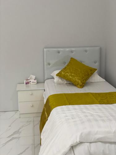 a bed with a yellow pillow and a night stand at شاليه الجبل الاحمر 3 in AlUla