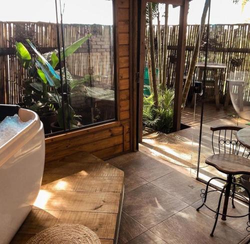 eine Terrasse mit Tisch und Stühlen und einem Fenster in der Unterkunft Pousada Villa Verde - Frente para a Praia do Farol in Ilha do Mel