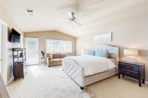 um quarto com uma cama branca e uma ventoinha de tecto em Carlotta Haven em Palm Desert