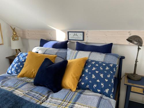 1 dormitorio con 1 cama con almohadas azules y amarillas en Das blaue Haus - ein Sommertraum und ein Wintermärchen, en Weiler-Simmerberg