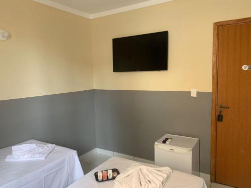 a room with two beds and a television on the wall at Hotel Barão Ribeirão in Ribeirão Preto