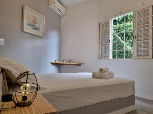 1 dormitorio con 1 cama con toallas en Casas com jacuzzi e churrasqueira a 500 metros da Praia do Perequê na Ilhabela, en Ilhabela