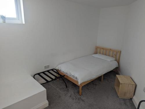 a small bedroom with a bed and a table at Flat with great transport links in Welling