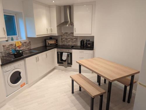 a kitchen with white cabinets and a table and a sink at Flat with great transport links in Welling