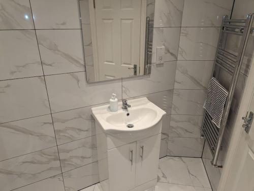 a white bathroom with a sink and a mirror at Flat with great transport links in Welling