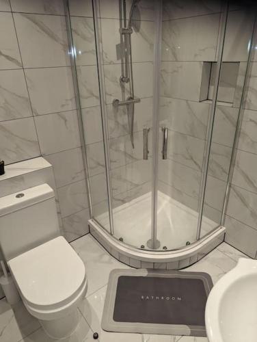 a bathroom with a shower and a toilet and a scale at Flat with great transport links in Welling