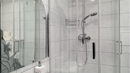 La salle de bains est pourvue d'une douche avec une porte en verre. dans l'établissement Spokojny Wypoczynek 5, à Ostrów Wielkopolski