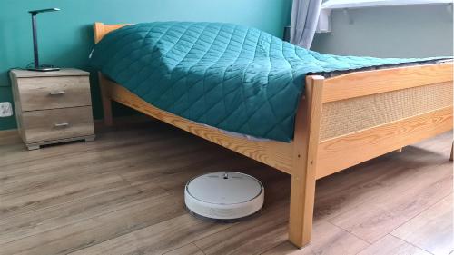 a bed with a green comforter and a scale on the floor at Spokojny Wypoczynek 4 in Ostrów Wielkopolski