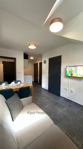 a living room with a couch and a tv on a wall at Apartma Zala, Golte in Mozirska Koča