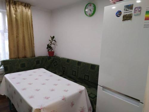 a room with a table and a green couch and a clock at SunRay Guest House-Hostel in Karakol