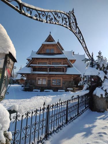 a fence in front of a house in the snow at Willa Tatrzański Zomecek in Kościelisko