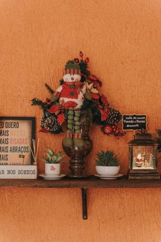 a shelf with a statue on it with plants and a sign at Pousada Pinhão e Poesia in Canela