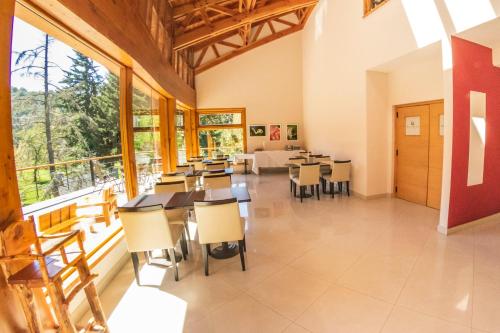 une salle à manger avec tables, chaises et fenêtres dans l'établissement Ruca Kuyen Golf & Resort, à Villa La Angostura