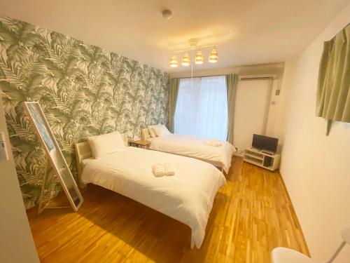 a bedroom with two beds and a wall mural at ラ・フィットヤマト101 in Meinohama