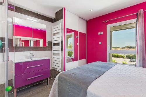 - une chambre rose avec un lit et un lavabo dans l'établissement Emplacement N°1 Port Nature 4, coursive vue mer, 2ème étage, village naturiste, au Cap d'Agde