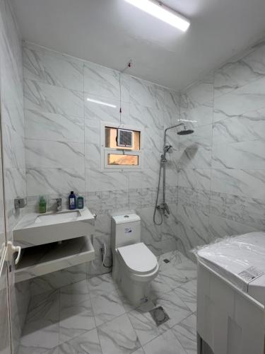 a white bathroom with a toilet and a sink at Hatta Royal Room in Hatta