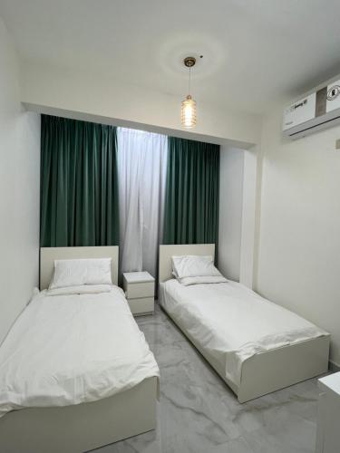 Hatta Royal Room في حتا: سريرين في غرفة مع ستائر خضراء