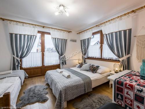 a bedroom with two beds and two windows at Domek z Góralską Duszą Śleboda in Jurgów