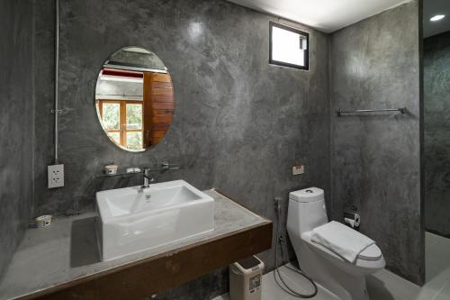 une salle de bain avec un lavabo, des toilettes et un miroir dans l'établissement The Loft Panwa Resort, à Panwa Beach