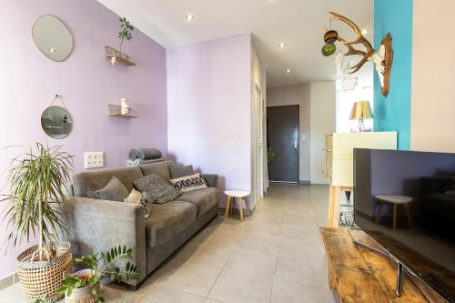 米洛的住宿－Hébergement Deluxe avec Grand Jacuzzi et Sauna Millau，带沙发和紫色墙壁的客厅