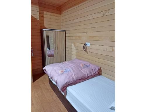 Cama pequeña en habitación con pared de madera en Cherry Village Resort, Pelling, Sikkim, en Pelling