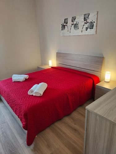 um quarto com uma cama vermelha com duas toalhas em Wagner house em Acireale