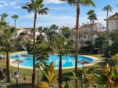 米哈斯科斯塔的住宿－Wonderful appartement on golf site near Marbella，享有棕榈树和建筑的游泳池的景色