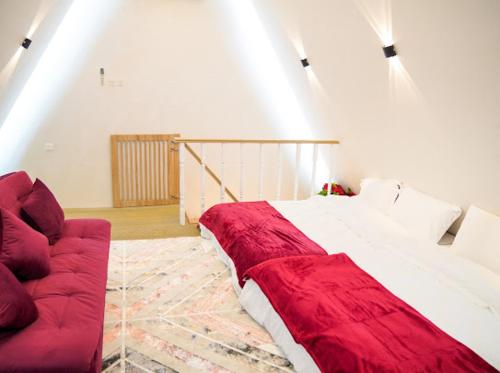 Red_Hut_Resort في Sharīyah: غرفة نوم بسرير كبير واريكة حمراء