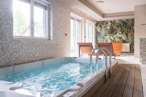 een grote badkamer met een groot bad met stoelen. bij Apartament z kominkiem.. and SPA, MyWeek in Polanica-Zdrój