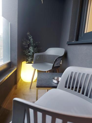 two white chairs and a table in a room with a plant at Supernova Royal Residence in Novi Sad