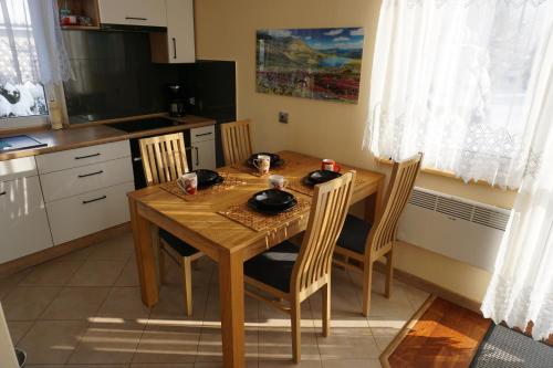 een keuken met een houten tafel met vier stoelen bij Uroczy Domek z Kominkiem in Lipowa