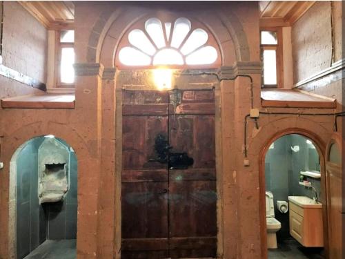 a bathroom with a large wooden door with a window at Eshel Mansion Near Cappadocia And Erciyes in Talas
