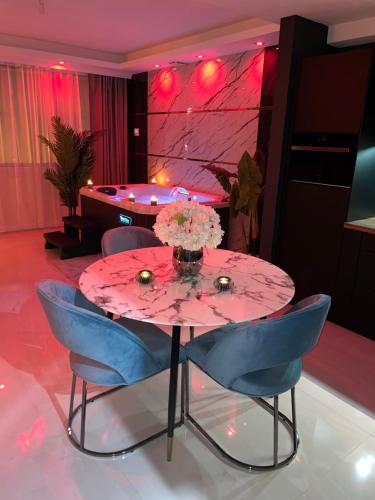 a pink table with blue chairs and a vase of flowers at NUITS D'HERMES & Spa in Chalon-sur-Saône