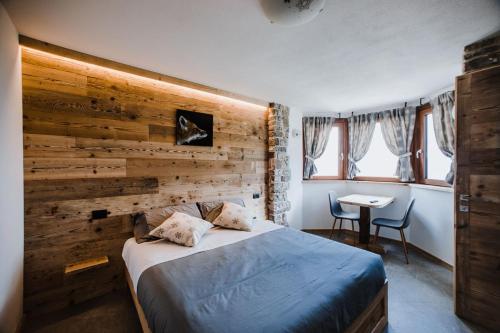 1 dormitorio con pared de madera, cama y mesa en Atelier della Montagna, en Zambla Alta