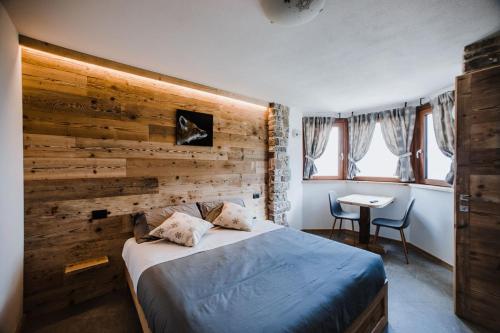 una camera da letto con una parete in legno, un letto e un tavolo di Atelier della Montagna a Zambla Alta