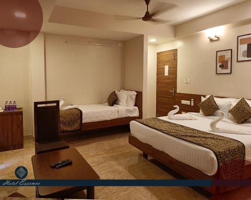 a hotel room with two beds and a table at Hotel ESSENCE in Vellore