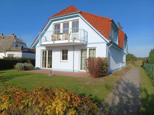 ein weißes Haus mit einem Balkon auf einem Hof in der Unterkunft An den Boddenwiesen I in Wustrow