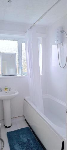 a white bathroom with a tub and a sink at excessivEDemand home in Thorne