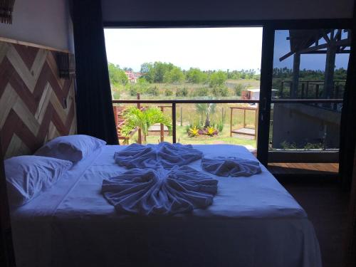 a bed in a room with a large window at Barong EcoVilla in Barra Grande