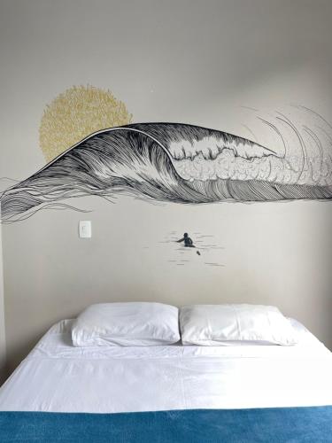 a bed with a painting of a wave on the wall at Pousada Low Tide maresias in Maresias