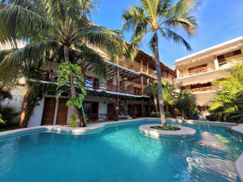 a swimming pool in front of a building with palm trees at Tierra Mia Boutique Hotel in Holbox Island