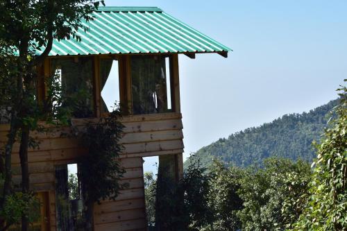 a tree house with a green roof at Bagar Trails in Nainital