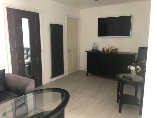 バーミンガムにあるCosy 3 Bedroom NEC House, Free WiFi, Netflix, Driveway Parking, Sleeps 6, Ideal for Families, Contractors & Corporates, Renovated To High Standard!のソファとテーブルとテレビのあるリビングルーム